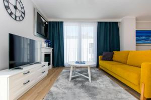 ein Wohnzimmer mit einem gelben Sofa und einem Tisch in der Unterkunft Villa Neptun - Exclusive Apartments in Danzig