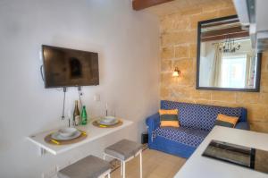 a living room with a blue couch and a tv at Charming house in the heart of Valletta CPAC1-3 in Valletta