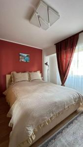 a bedroom with a white bed with a red wall at Apartament de lux, zona centrala in Gura Humorului