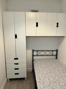 a bedroom with a bed and white cabinets at Wulfstan House Quiet, Neat, Comfy - 2 min to Central line, Westfield, Notting hill in London