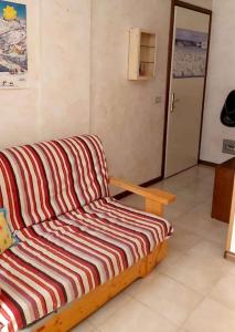 - un canapé rayé dans une chambre avec porte dans l'établissement Appartamento di Giulio & Giorgia, à Predazzo