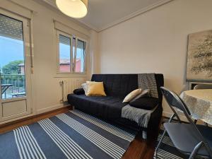 uma sala de estar com um sofá preto e uma janela em C12A01 Coqueto apartamento con piscina y garaje em Suances