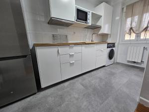 uma cozinha com armários brancos e um micro-ondas em C12A01 Coqueto apartamento con piscina y garaje em Suances