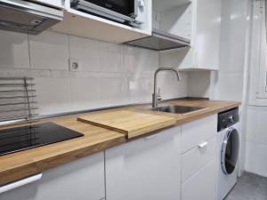 uma cozinha branca com um lavatório e um fogão em C12A01 Coqueto apartamento con piscina y garaje em Suances