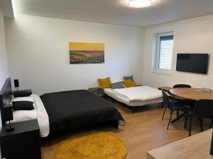 a room with two beds and a table and a tv at Apartmány Kyjov in Kyjov