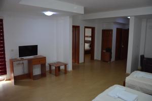 ein Wohnzimmer mit einem TV und einem Schreibtisch mit einem TV in der Unterkunft Arabella Hotel in Kičevo