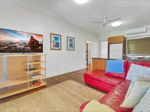 a living room with a red couch and a kitchen at Picnic Bay Apartments Unit 3 in Picnic Bay