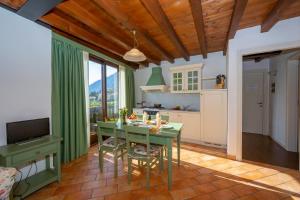 a kitchen with a green table with chairs and a television at Mimosa in Hilly area - Happy Rentals in Gargnano