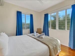 a bedroom with a large bed with blue curtains at Picnic Bay Apartments Unit 3 in Picnic Bay