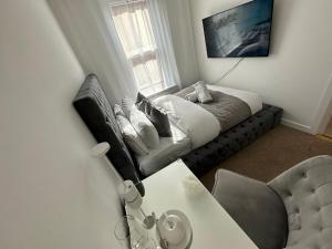 a living room with a couch and a table at The smaller new refurbished room 5 min from beach/parking in Guests house. in Bournemouth