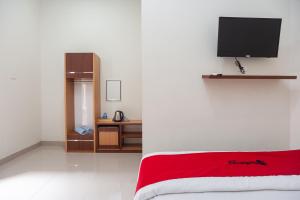 ein Schlafzimmer mit einem Bett und einem TV an der Wand in der Unterkunft RedDoorz @ Jalan Urip Sumoharjo Lampung 2 in Lampung