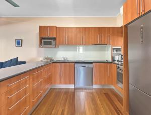 une cuisine avec des placards en bois et des appareils en acier inoxydable dans l'établissement Picnic Bay Apartments Unit 4, à Picnic Bay