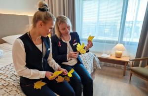 Dos mujeres sentadas en una cama jugando con hojas en Original Sokos Hotel Lakeus Seinäjoki, en Seinäjoki