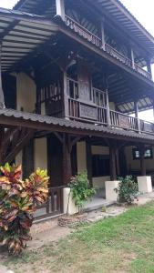 a large wooden building with a balcony and plants at Rumah Jepun in Mataram