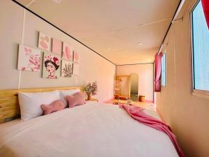 1 dormitorio con 1 cama blanca grande con almohadas rosas en Suly's Village Phan Thiết en Phan Thiet