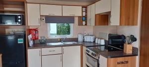 cocina con armarios blancos y nevera negra en A5 Avocet Rise en Goodrington