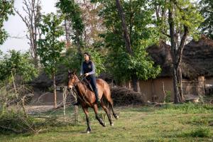 Una donna che cavalca un cavallo in un campo di Aalia Jungle Retreat and Spa, Bandarjudh, Haridwar - Araiya Anthology a Dehradun