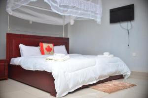 a bedroom with a bed with white sheets and a television at Elgon Palace Hotel - Mbale in Mbale