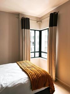 1 dormitorio con cama y ventana grande en Staycation Sandton Apartment, en Johannesburgo