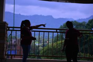 two women standing on a balcony looking at the mountains at Elgon Palace Hotel - Mbale in Mbale