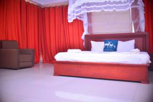 Schlafzimmer mit einem Bett mit roten Vorhängen und einem Stuhl in der Unterkunft Elgon Palace Hotel - Mbale in Mbale