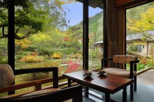 a room with a table and chairs and a view of a garden at Tachibanaya in Tsuruoka