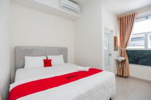 a white bedroom with a red blanket on a bed at RedDoorz @ Kali Balok Lampung in Geruntang
