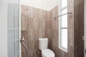 a bathroom with a toilet and a window at RedDoorz @ Kali Balok Lampung in Geruntang