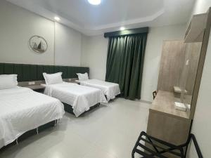 a hotel room with two beds and a chair at ديار المشاعر للشقق المخدومة Diyar Al Mashaer For Serviced Apartments in Mecca