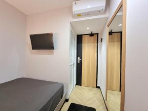 Check Inn at Citarum في سيمارانغ: غرفة نوم صغيرة بها سرير وتلفزيون بشاشة مسطحة