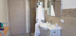 biała łazienka z umywalką i prysznicem w obiekcie Il Terrazzo di Apollo w mieście Noto