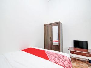- une chambre avec un lit, une commode et un miroir dans l'établissement OYO 92946 Dekna Homestay Syariah, à Pekanbaru