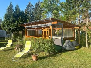 a small cabin with yellow chairs in a yard at Holiday home with Jakuzzi and Sauna in Kisoroszi