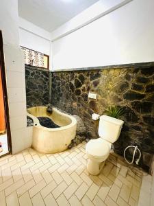 a bathroom with a toilet and a bath tub at Pondok Wisata Grya Sari in Banjar