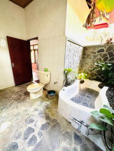 a bathroom with a tub and a toilet in it at Pondok Wisata Grya Sari in Banjar