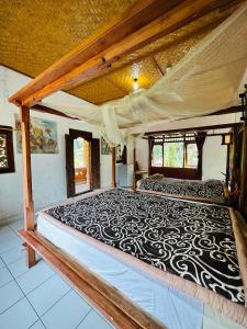 ein großes Bett mit einer schwarzen und weißen Bettdecke in der Unterkunft Pondok Wisata Grya Sari in Banjar