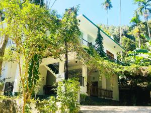 Un edificio blanco con árboles delante. en Misty Elegance - Ella., en Ella