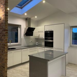 a kitchen with white cabinets and black appliances at Przestronny Apartament in Żagań +22 photos
