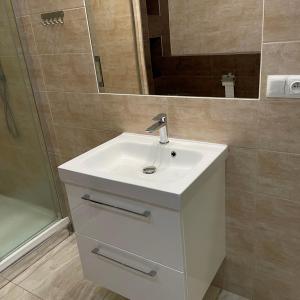 ein Badezimmer mit einem weißen Waschbecken und einem Spiegel in der Unterkunft Przestronny Apartament in Sagan