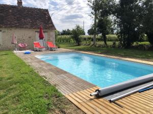 einen Pool mit einer Holzterrasse neben einem Haus in der Unterkunft Villa d'une chambre avec piscine privee jardin amenage et wifi a Betz le Chateau in Betz-le-Château