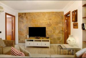 un soggiorno con TV su un muro di pietra di Magara suites Las Canteras a Guanarteme