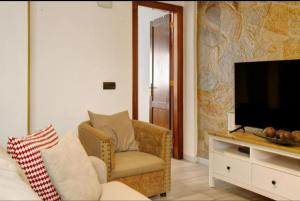 un soggiorno con sedia e TV di Magara suites Las Canteras a Guanarteme Altre 2 foto