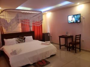a bedroom with a bed and a tv on the wall at Elgon Palace Hotel - Mbale in Mbale +7 photos
