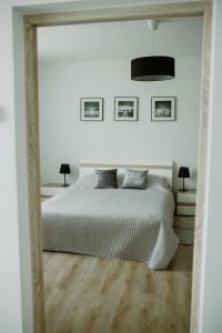 een witte slaapkamer met een bed en een spiegel bij Apartament Magnolia -centrum in Tarnów