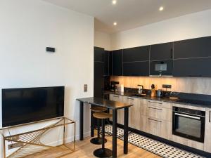 una cucina con armadi neri, tavolo e televisore di Le Royal XIX Dinard vue mer luxe a Dinard