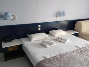 2 Betten in einem Hotelzimmer mit Handtüchern und Lampen in der Unterkunft Skion Palace Beach Hotel-Bungalows & Boutique Hotel in Nea Skioni