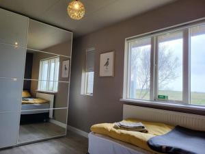 a bedroom with a mirror and a bed and a window at Sibbu Hús in Brjansstadir