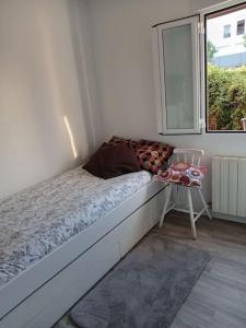 Cama en habitación con ventana y silla en Preciosa casa bi-familiar al lado de Donosti. en Irún