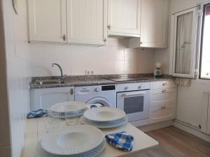 a white kitchen with three plates on a table at Preciosa casa bi-familiar al lado de Donosti. in Irún