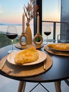 a table with two plates of food and glasses of wine at Bohoroom in Chakvi +11 photos